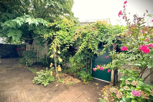 un jardin avec des fleurs roses et une porte verte dans l'établissement L'Octroi-Maison au calme avec jardin, à Nantes