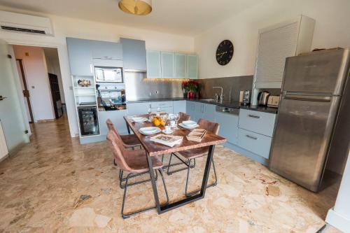 une cuisine avec une table avec des chaises et un réfrigérateur dans l'établissement Valentina - Sea view Luminous Calm - by TGB, à Ajaccio