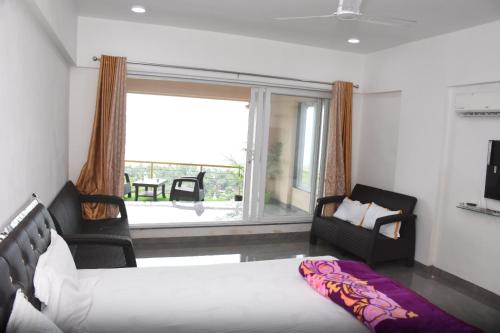 a bedroom with a bed and two chairs and a large window at Nikhat villa 61 in Harnai