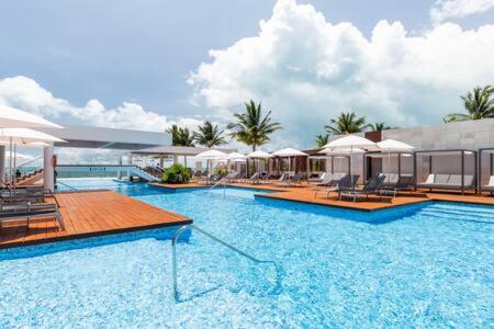 a large swimming pool with chairs and umbrellas at 2BR Apartment with Beach Club in Cancún