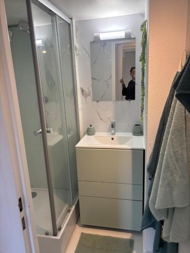 un homme prenant une photo d'une salle de bains avec lavabo et douche dans l'établissement Mazet 33, au Plan-de-la-Tour