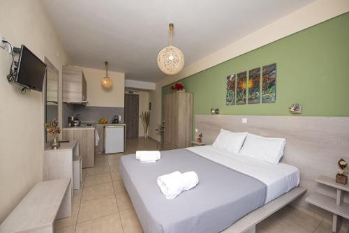 a bedroom with a large white bed and a kitchen at Fantastico Studios in Kalamitsi