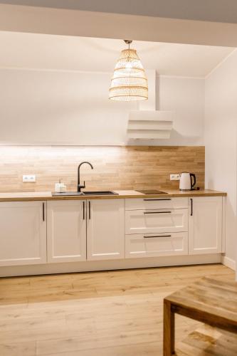 a kitchen with white cabinets and a sink at Kosa Śpiew Joga i Spa in Kosewo