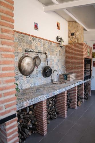 a kitchen with a brick wall with pots and pans at Cortijo Los Santeros in Castril