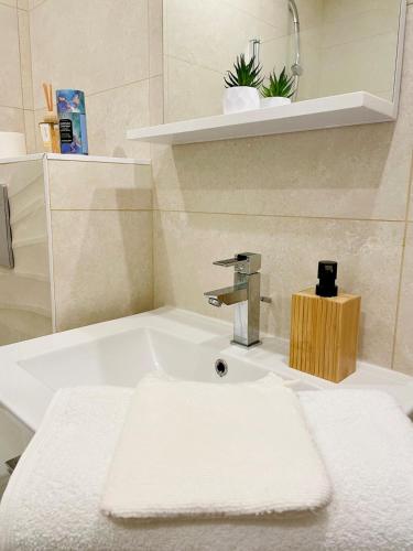 La salle de bains est pourvue d'un lavabo et d'une serviette blanche. dans l'établissement Grand studio Ô Joie, à Auxerre