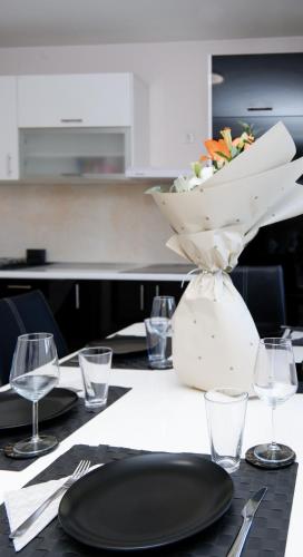 a table with plates and glasses and a vase with flowers at Place to Be - Modern Jacuzzi House in Vozdovac in Belgrade