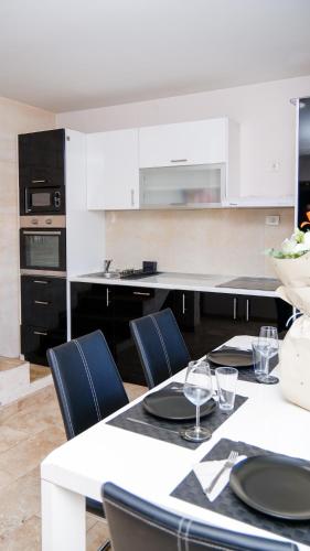 a kitchen with white cabinets and a table with chairs at Place to Be - Modern Jacuzzi House in Vozdovac in Belgrade