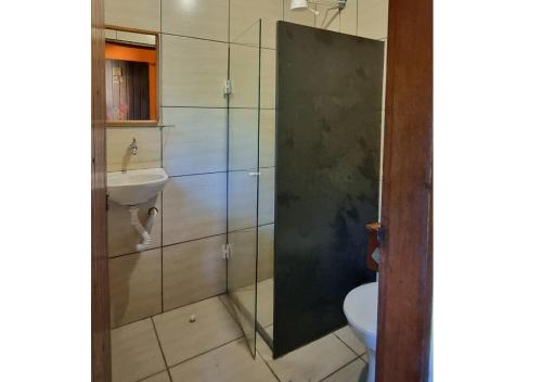 a bathroom with a shower with a sink and a toilet at Maresias Hostel & Suites in Maresias