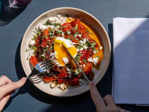 a person eating a bowl of food with a fork and knife at TRIBE Paris Clichy in Clichy