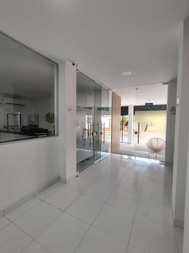 a white hallway with glass walls and a chair at Hotel Astor Cucuta in Cúcuta