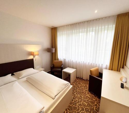 a hotel room with a large bed and a chair at Parkhotel Green Garden in Bad Hersfeld
