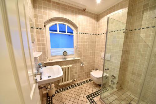 un bagno con lavandino, WC e finestra di Ferienwohnung Strandnest in der Villa Gudrun Binz a Binz