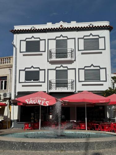 un edificio con ombrelli rossi davanti a una fontana di Chalé do Tejo a Moita