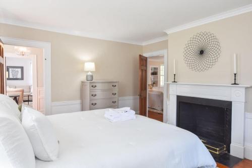 a bedroom with a white bed and a fireplace at Stylish Retreat 2 mi to Beach in Yarmouth