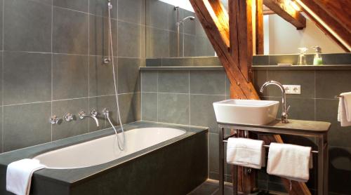 a bathroom with a bath tub and a sink at Hotel Maurerhansl in Dießen am Ammersee