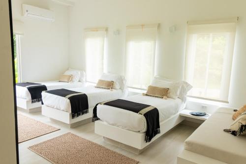 two beds in a white room with windows at Selva Serena in Anapoima