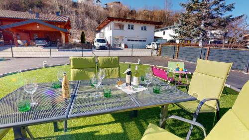 a table and chairs with wine glasses on the grass at Villa am Achenweg in Saalfelden am Steinernen Meer