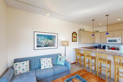 a living room with a blue couch and a kitchen at Ninos Al Mar in Rockaway Beach