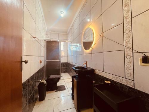 a bathroom with a toilet and a sink and a mirror at Apto Cobertura Santa Rosalia in Poços de Caldas