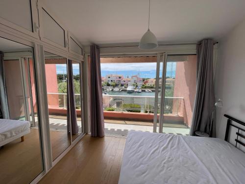 - une chambre avec un lit et une grande fenêtre avec vue dans l'établissement DOUCEUR DU RIVAGE - 6pers - Histoire de Clés, au Cap d'Agde
