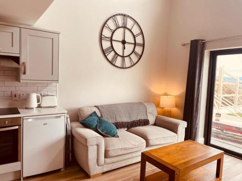 a living room with a couch and a clock on the wall at Teach Máire, Downings in Downings