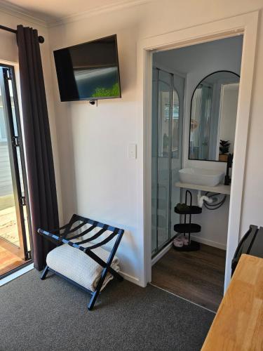 a bathroom with a chair and a sink and a mirror at Studio on Charles in Tauranga