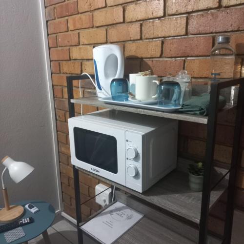 a microwave on a shelf with dishes on it at Tanya's Haven Guesthouse in Klerksdorp