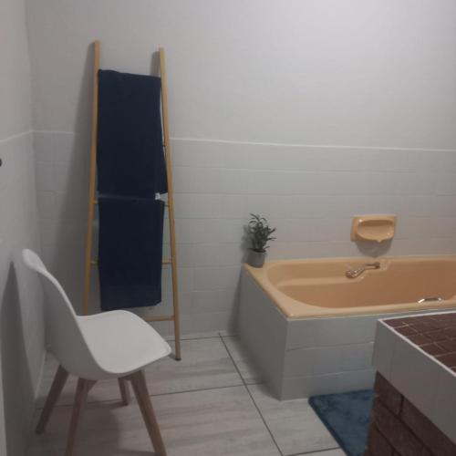 a bathroom with a tub and a chair and a sink at Tanya's Haven Guesthouse in Klerksdorp