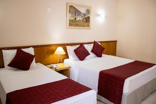 a hotel room with two beds and a lamp at Hotel Dan Inn Araraquara by Nacional Inn in Araraquara