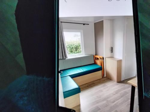 Cette petite chambre dispose d'une fenêtre et d'un banc bleu. dans l'établissement Mobil home, à Talmont-Saint-Hilaire