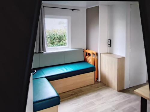 Cette petite chambre dispose d'une fenêtre et d'un banc bleu. dans l'établissement Mobil home, à Talmont-Saint-Hilaire