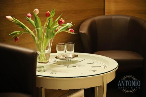 a table with a vase of flowers and two glasses on it at Antonio Old Town Residence in Prešov