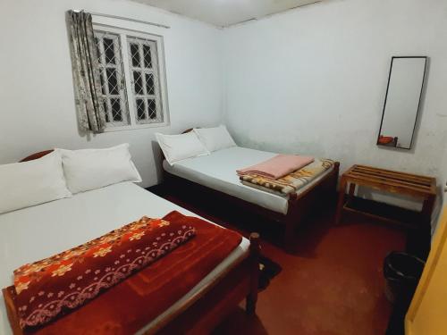 a room with two beds and a mirror and a window at Green Villa in Nuwara Eliya