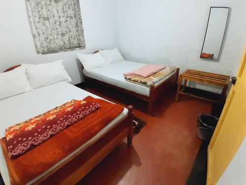 two beds in a room with a mirror and a table at Green Villa in Nuwara Eliya