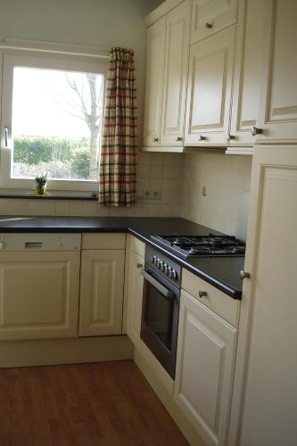 a kitchen with white cabinets and a stove and a window at Huize Polderzicht aan het Grevelingenmeer in Battenoord