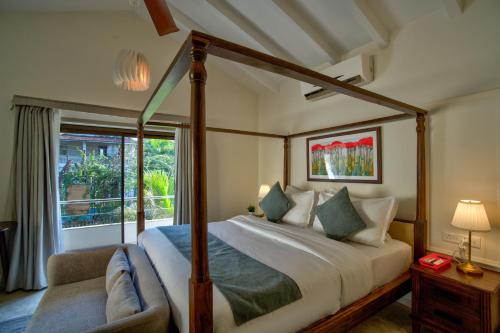 a bedroom with a canopy bed and a window at Villa Savaaya Assagao Goa in Assagao