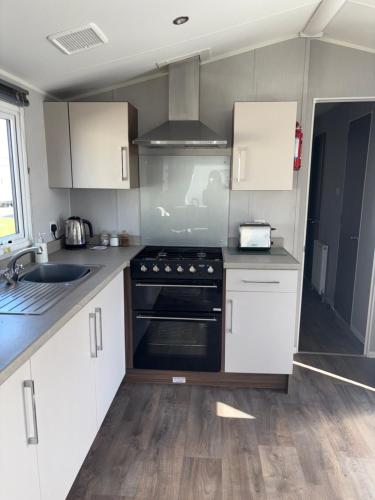 a kitchen with white cabinets and a stove top oven at McCanns Caravan Marton Mere in Blackpool
