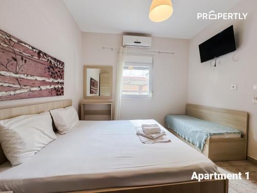 a bedroom with a large bed and a tv at SeaYa Beach Retreat - Private Parking in Nea Kalikratia