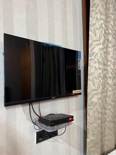 a flat screen tv hanging on a wall at In the woods homestay Lansdowne in Lansdowne