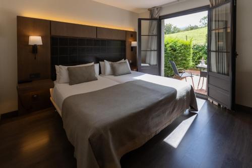 a bedroom with a large bed and a large window at La Piconera Hotel & Spa in Ribadesella