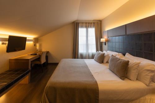 a hotel room with a large bed and a desk at La Piconera Hotel & Spa in Ribadesella