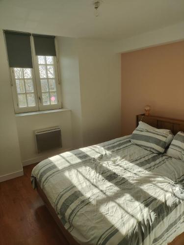 - une chambre avec un lit doté d'une couette à rayures et d'une fenêtre dans l'établissement appartement centre ville, à Limoges