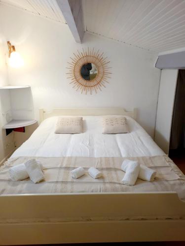 - un grand lit blanc avec deux oreillers et un miroir dans l'établissement Au petit bonheur parking gratuit, à Cavalaire-sur-Mer