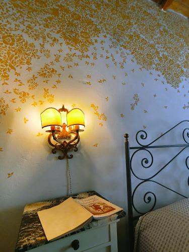 a lamp on a wall next to a table with a book at La Funambola BB in Poggio Alla Croce