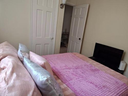 a bedroom with a bed with a pink comforter at ShayBnB in Portsmouth