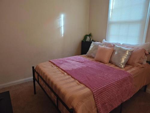 a bedroom with a bed with pink sheets and a window at ShayBnB in Portsmouth