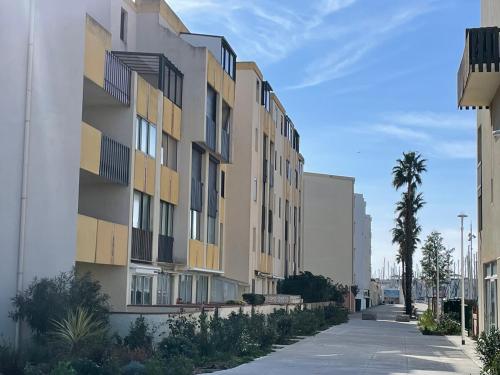 an apartment building on a street with palm trees at Charmant Appartement sur le Port de Port Leucate in Leucate-Plage
