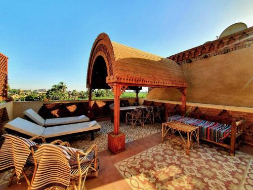 un patio al aire libre con cenador, mesas y sillas en Villa Rosamund, en Luxor