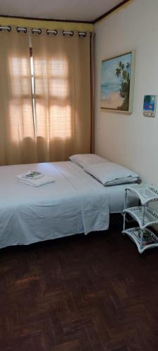 a bedroom with a large bed with a window at Quarto econômico in São Luiz do Paraitinga