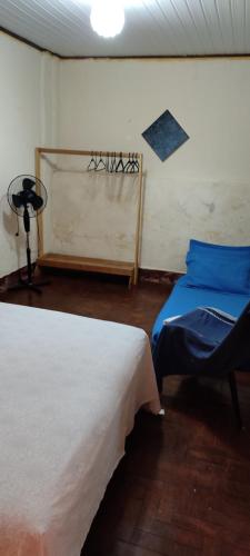 a room with two beds and a chair in it at Quarto econômico in São Luiz do Paraitinga